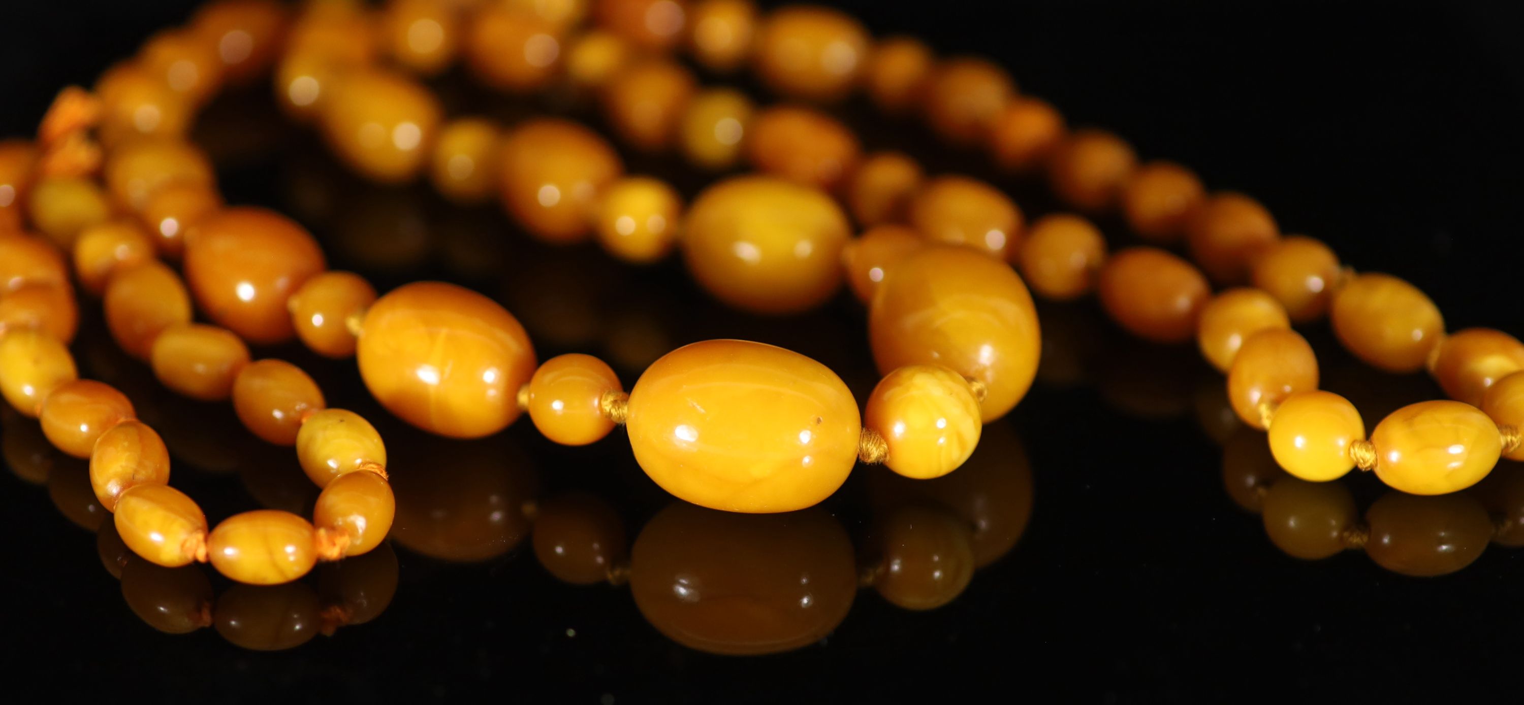 A single strand graduated oval amber bead necklace with round bead spacers